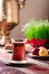 Novruz setting table decoration, tea in  tulip shape glass on ethnic motives rustic table cloth with wheat grass, dyed eggs, traditional sweets, samovar, new year sring celebration, nature awakening