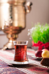 Novruz setting table decoration, tea in  tulip shape glass on ethnic motives rustic table cloth with wheat grass, dyed eggs, traditional sweets, samovar, new year sring celebration, nature awakening