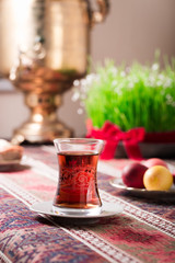 Novruz setting table decoration, tea in  tulip shape glass on ethnic motives rustic table cloth with wheat grass, dyed eggs, traditional sweets, samovar, new year sring celebration, nature awakening
