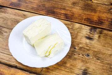 Fresh farm piece of butter on a white plate on wooden background Farm products Plate on the left at photo
