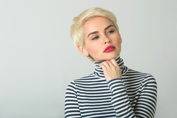 beautiful young girl with short hairdo on a light background with a pensive face