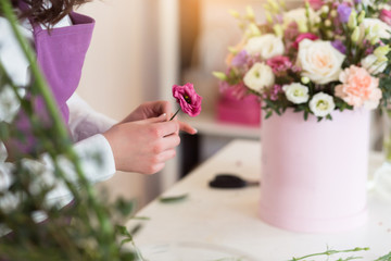 Young happy florist making fresh flowers arrangement in gift box for a holidays