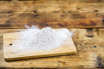Close-up heap with wheat flour coarse on a wooden board.