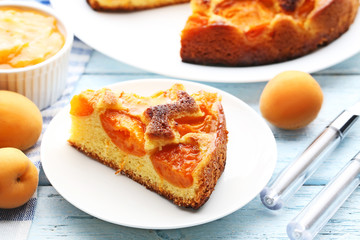Slice of apricot pie with fruits on blue wooden table