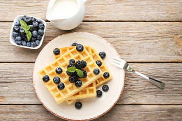 Sweet waffle with berries and jar of milk on grey wooden table