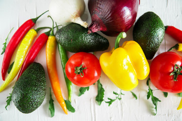 Set of fresh vegetables on a light background: tomatoes, peppers, chili, avocado, greens, onion. The concept of natural healthy eating, vegetarianism, vitamins.