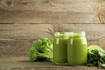 Bottles of juice with broccoli and cucumber on grey wooden table