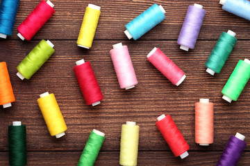 Colourful thread spools on brown wooden table