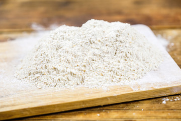 Close-up heap with rye flour coarse on a wooden board.