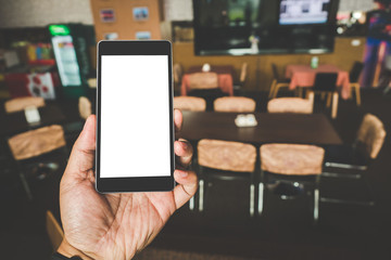 Hand holding black mobile smart phone with blank black screen in coffee shop cafe. technology and lifestyle concept.