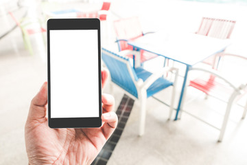 Hand holding black mobile smart phone with blank black screen in coffee shop cafe. technology and lifestyle concept.