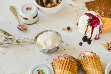 A Kit For Making Ice Cream: Spoon For Ice Cream, Ice Cream Cones, Jam, Topping, Chocolate, Sprinkles, Coconut Shavings. on white background. Concept Ideas For A Gift With Their Own Hands.