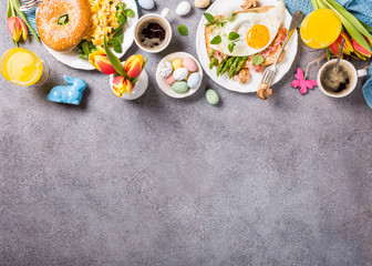 Easter breakfast flat lay with scrambled eggs bagels, orange tulips, bread toast with fried egg and...