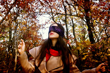 Beautiful girl with blindfold looks to the sky in the forest