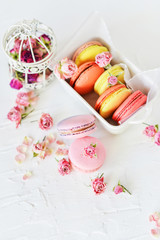 Delicate Fresh Colorful French Macaroons In Pastel Colors With Flowers Roses On A Light Textile Background, Top View
