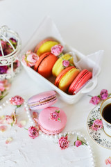 Dessert: A Delicate Fresh Colorful French Macaroons In Pastel Colors With Flowers Roses On A Light Textile Background, Top View