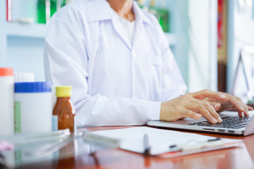 close up pharmacist woman hand typing on laptop for search information of medicine , health concept