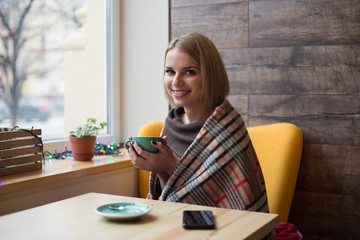 Woman drinking coffee in the morning at cafe. Soft focus on the eyes. Sellphone on table.