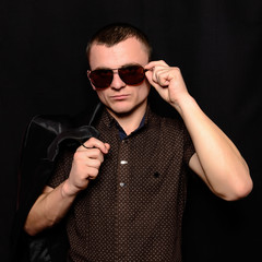 Studio portrait of a young guy with a short haircut in brown sunglasses