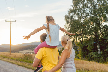 Familie trägt Kind auf den Schultern bei Sommer Spaziergang