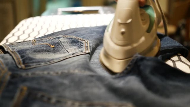 a woman ironing jeans with an iron