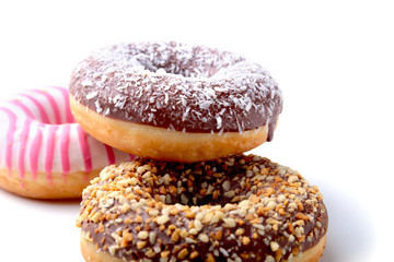 Assorted doughnuts in the glaze, colorful sprinkles and nuts on a white background.