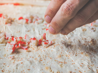 Preparation of rolls of crab meat, cheese and herbs in lavash.
