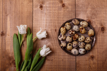 Tulips flowers and eggs decoration on wooden background. Top view, text space