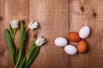 Tulips flowers and eggs decoration on wooden background. Top view, text space