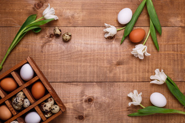 Tulips and eggs in wooden box on the table. Top view, text space