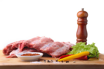 Raw Ribs on a rustic cutting board with salt, pepper and grinder for spices . White Background for copy space. Top View.