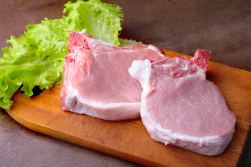 Raw chop on a rustic cutting board with salt, pepper and grinder for spices . for copy space. Top View.