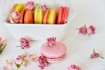 Fototapeta na wymiar Dessert: A Delicate Fresh Colorful French Macaroons In Pastel Colors Gift Box Flowers Roses On Light Textiles Background