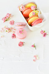 Dessert: A Delicate Fresh French Macaroons In Pastel Colors Gift Box With Flowers Roses On A Light Textile Background