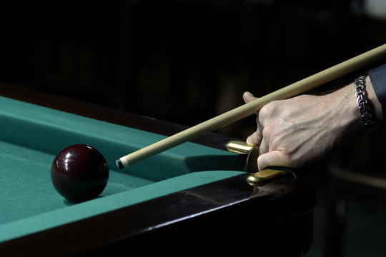 A player's arm gets ready to stroke a ball with a cue