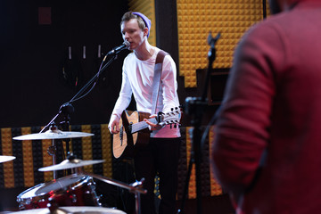 Portrait of young musician performing in dim recording studio while making new album with his band, copy space