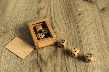Wooden round corner dice six sided dots set for playing with box on wooden board surface as background