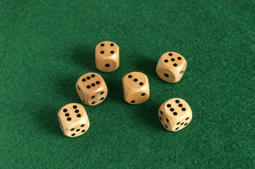 Wooden round corner dice six sided dots set for playing on dark green poker table felt cloth surface as background
