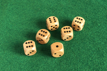 Wooden round corner dice six sided dots set for playing on dark green poker table felt cloth surface as background