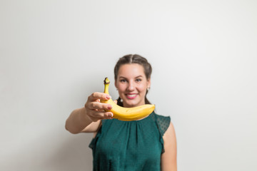 Pretty woman stretches out banana fruit to camera and smiles