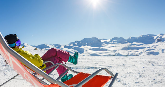 Image of sporty woman in helmet sitting at snowy resort