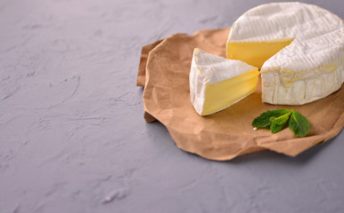 Tasty slice of a cheese on a stone grey table. Food background with cheese.