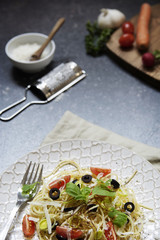 Bunte Teller Spaghetti mit Basilikum, Tomaten, Oliven vertikal mit Gemüse und Zubehör für die Küche