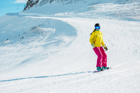 Picture of sports girl in helmet riding snowboard from mountain slope