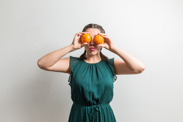 Funny teenager holds fruits over her eyes