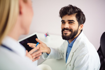 Portrait of young smiling male doctor talking with his colleague.