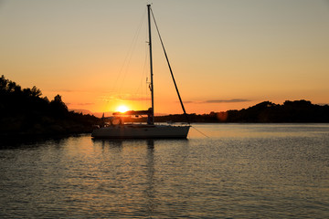 Beautiful sunset sailboat anchoring in a bay near Porto Heli, Peloponnese, Greece.