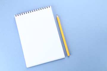 Top view image of open notebook with blank pages and coffee on blue background, ready for adding or mock up. Still life, business, office supplies or education concept.