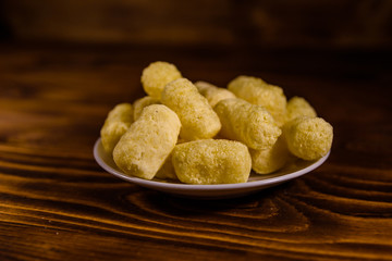 Ceramic plate with corn sticks on wooden table