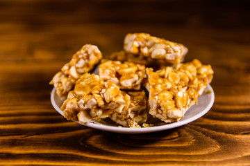 Ceramic plate with peanut brittles on wooden table.